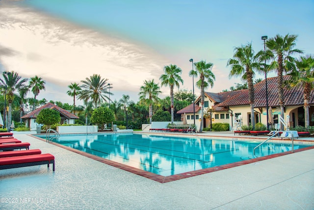 pool at dusk with a patio area