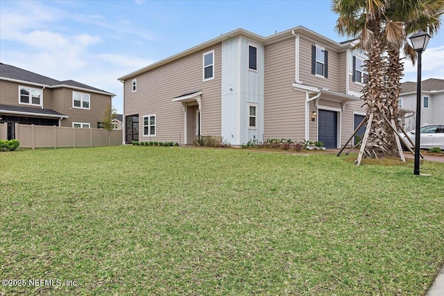 view of front of home with a front yard, a garage, and fence