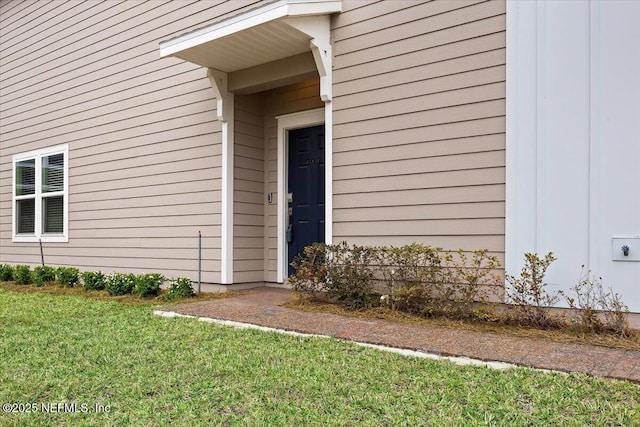 doorway to property featuring a lawn