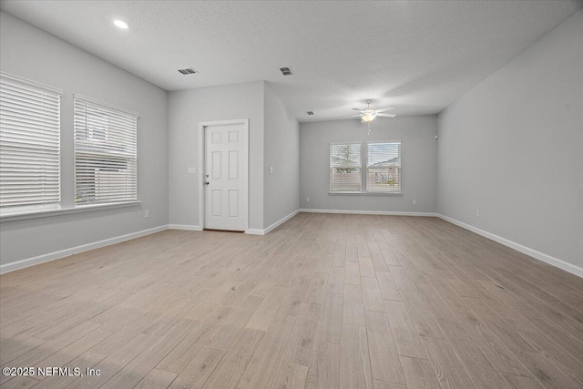 empty room featuring baseboards, light wood-type flooring, and a textured ceiling