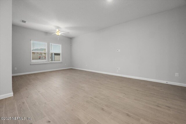 unfurnished room featuring visible vents, baseboards, wood finished floors, a textured ceiling, and a ceiling fan