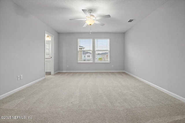 empty room featuring light carpet, visible vents, a textured ceiling, and baseboards