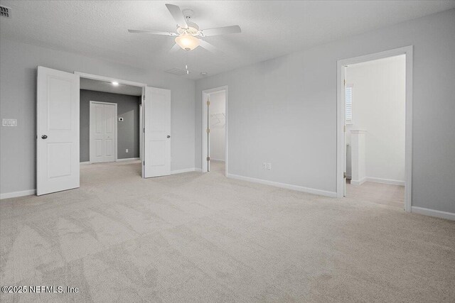 unfurnished bedroom with a walk in closet, baseboards, visible vents, and light carpet