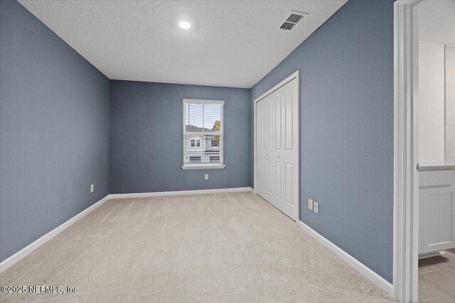 unfurnished bedroom featuring visible vents, a textured ceiling, and baseboards