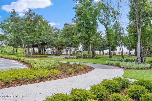 view of property's community with playground community, a lawn, and uncovered parking