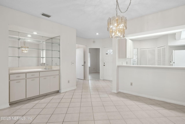 interior space featuring light countertops, hanging light fixtures, visible vents, freestanding refrigerator, and a sink