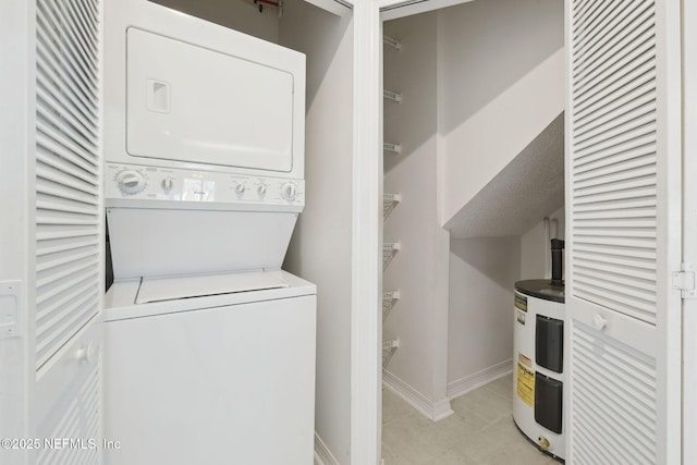 laundry area featuring light tile patterned floors, electric water heater, stacked washer and dryer, laundry area, and baseboards