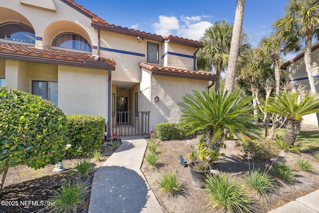 exterior space featuring a tiled roof, a gate, and stucco siding