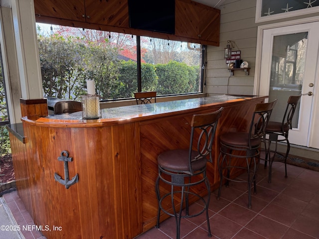 bar with wood walls, a dry bar, and tile patterned floors