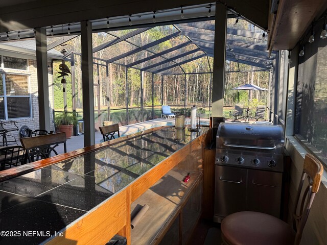 view of patio with a lanai, outdoor dining area, an outdoor kitchen, and grilling area