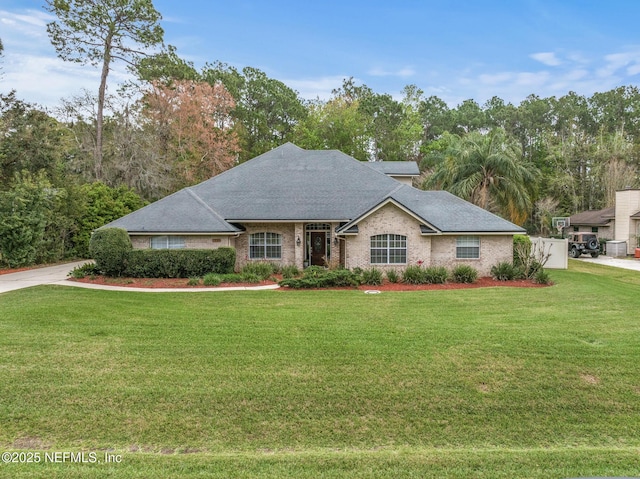 ranch-style house featuring a front yard, roof with shingles, and brick siding