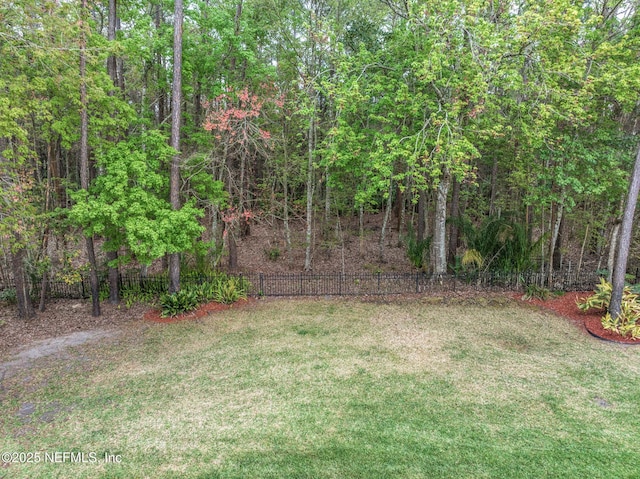 view of yard featuring fence and a wooded view