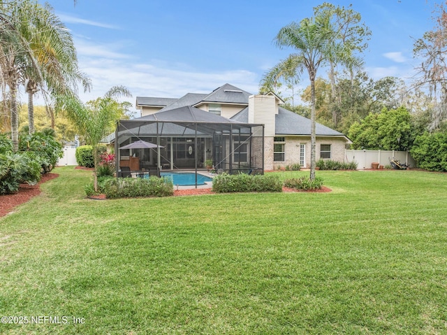 rear view of property featuring a lanai, a fenced backyard, a lawn, and a chimney