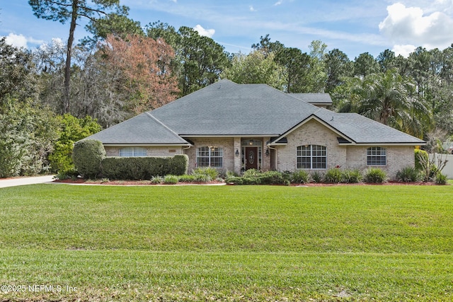 view of front of house featuring a shingled roof, a front yard, and brick siding