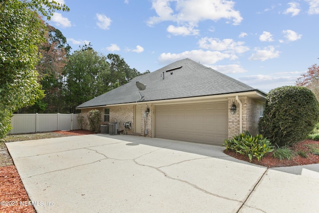 view of front facade featuring brick siding, roof with shingles, concrete driveway, an attached garage, and fence