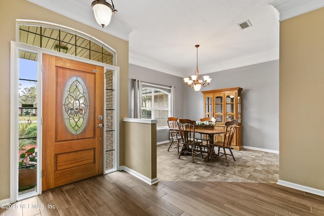 foyer entrance featuring an inviting chandelier, crown molding, visible vents, and wood finished floors