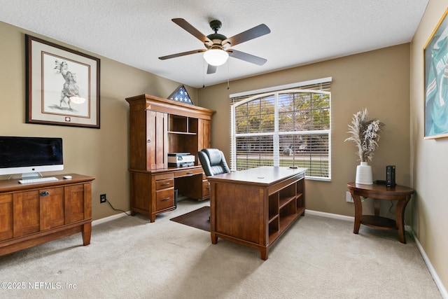 office space with light carpet, ceiling fan, baseboards, and a textured ceiling