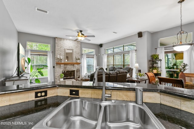 kitchen with a fireplace, a sink, visible vents, and a healthy amount of sunlight