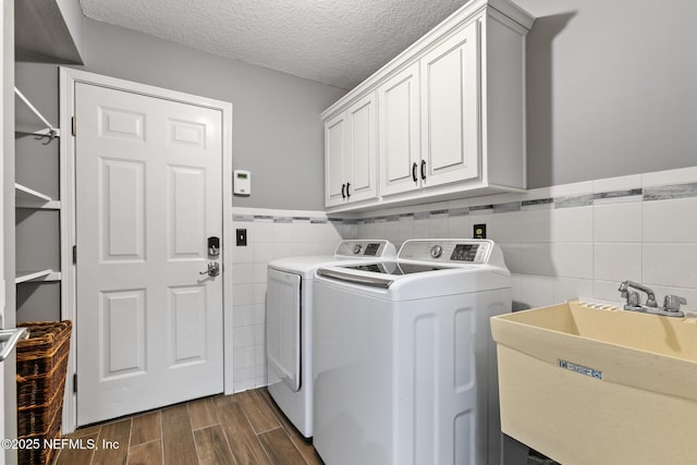 clothes washing area featuring wood finish floors, cabinet space, a sink, a textured ceiling, and separate washer and dryer