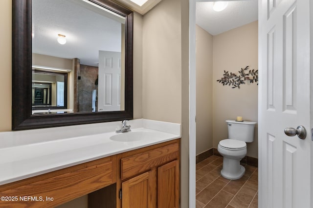 bathroom with toilet, a textured ceiling, vanity, and tile patterned floors