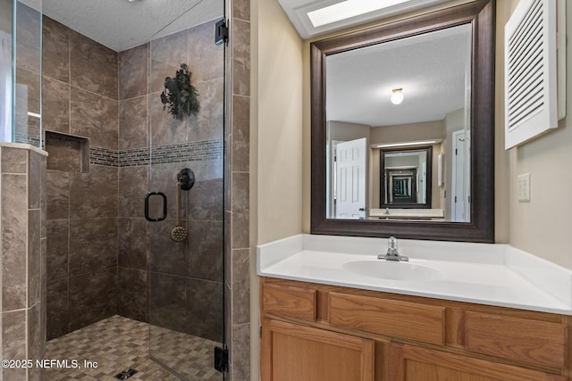 full bath featuring a shower stall, vanity, and a textured ceiling