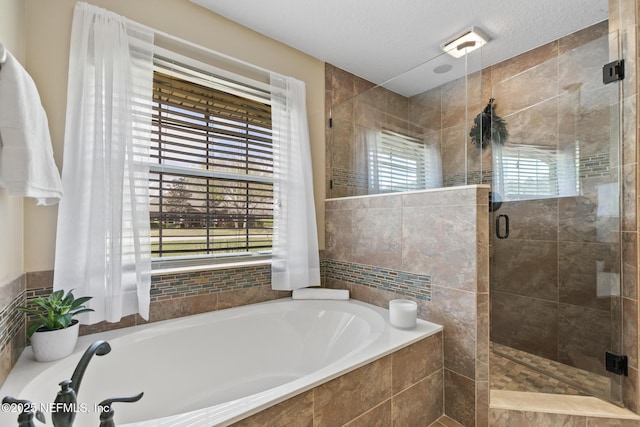 full bathroom featuring a stall shower, a garden tub, and a textured ceiling