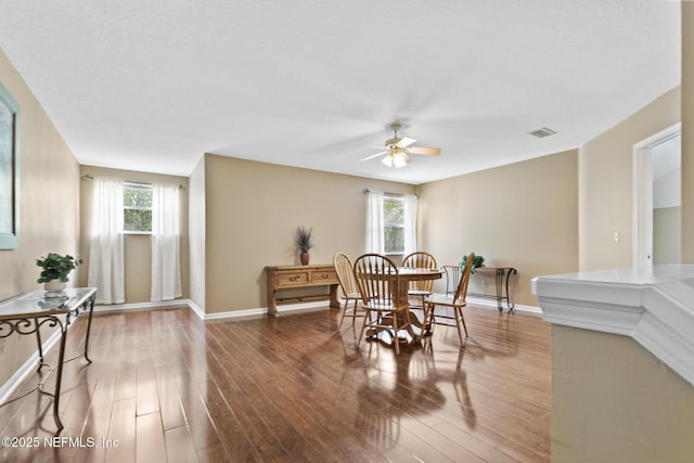 dining space with baseboards, wood finished floors, visible vents, and a healthy amount of sunlight