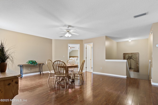 dining room featuring a textured ceiling, wood-type flooring, visible vents, and baseboards