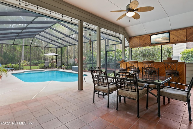 outdoor pool featuring glass enclosure, a ceiling fan, and a patio