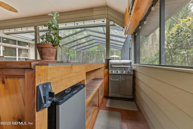 view of patio / terrace featuring glass enclosure, grilling area, and an outdoor kitchen