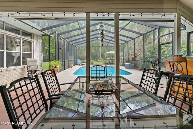 view of patio with outdoor dining space, glass enclosure, and an outdoor pool