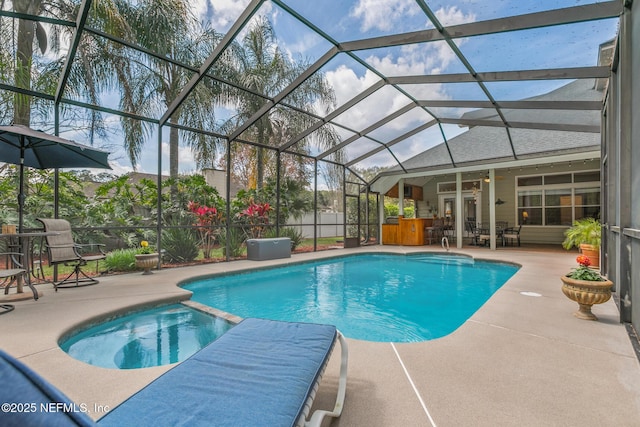 view of pool featuring a patio area, a pool with connected hot tub, and glass enclosure