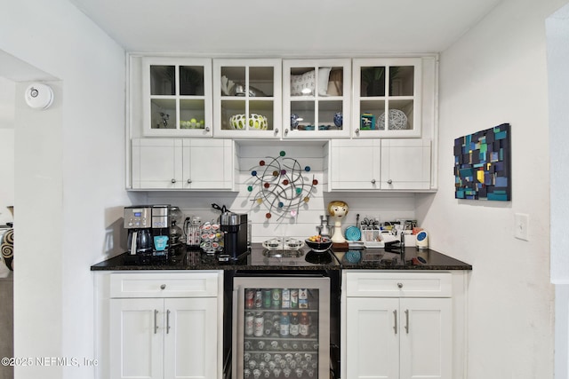 bar featuring wine cooler, white cabinetry, and dark stone counters