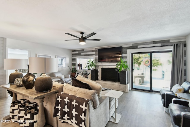 living room featuring a fireplace, light hardwood / wood-style flooring, a textured ceiling, and a healthy amount of sunlight