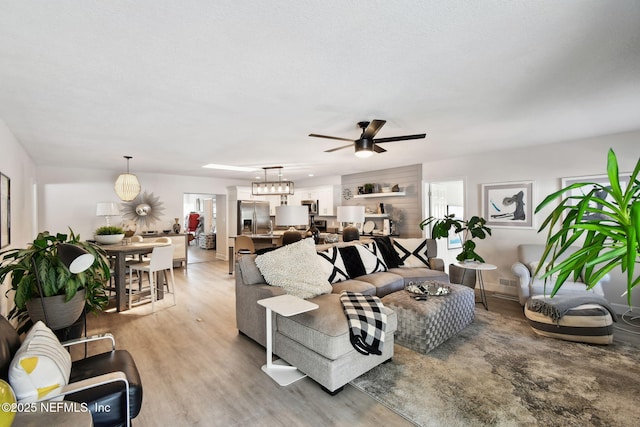 living room featuring ceiling fan with notable chandelier, a healthy amount of sunlight, and hardwood / wood-style floors