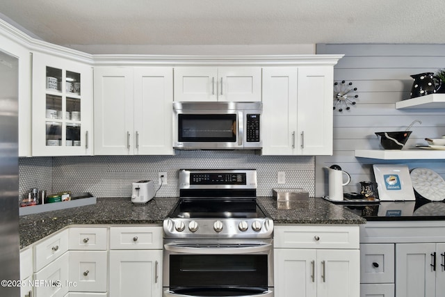 kitchen featuring white cabinetry, appliances with stainless steel finishes, and dark stone counters