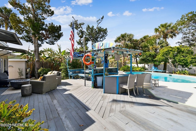 wooden terrace with a fenced in pool and an outdoor living space with a fire pit