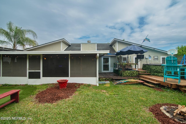 rear view of house featuring a yard, a deck, a chimney, and a sunroom