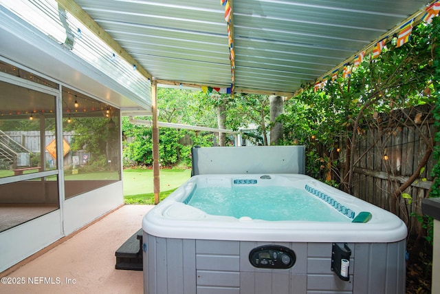 view of patio featuring fence, a sunroom, and a hot tub