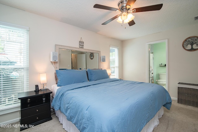 bedroom with a textured ceiling, ensuite bath, baseboards, and light carpet