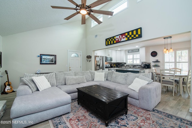 living room featuring a textured ceiling, light wood-type flooring, and ceiling fan