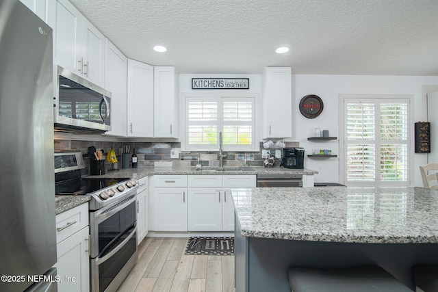 kitchen featuring a sink, stainless steel appliances, backsplash, and a wealth of natural light