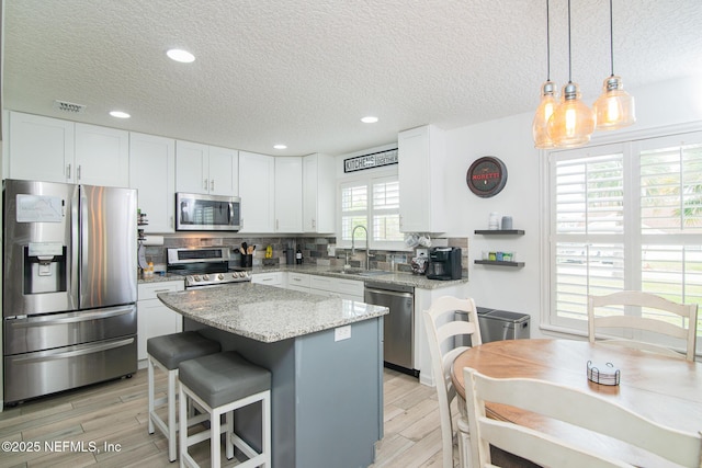 kitchen with a sink, stainless steel appliances, light wood-type flooring, and tasteful backsplash