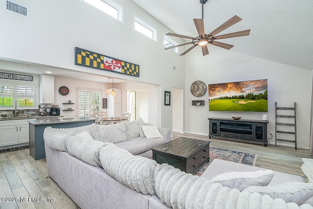 living area with a ceiling fan, visible vents, a healthy amount of sunlight, and light wood-type flooring