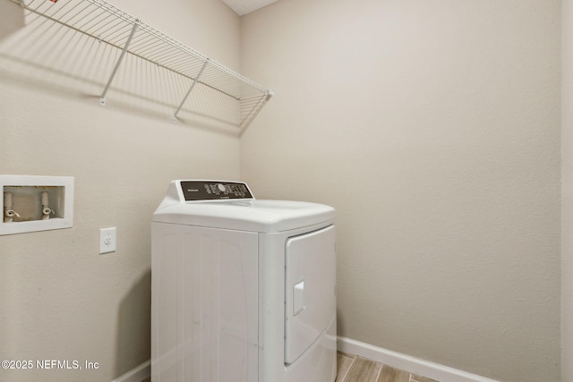 clothes washing area with washer / dryer, laundry area, baseboards, and wood finished floors