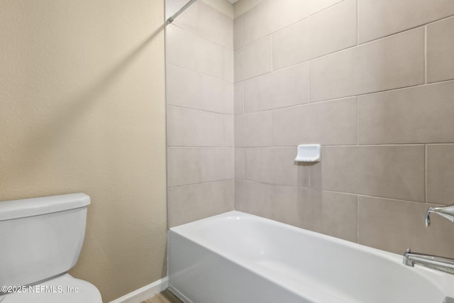 bathroom with toilet, baseboards, and a bathtub