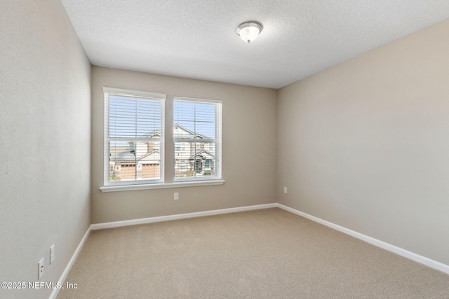 carpeted spare room with a textured ceiling and baseboards