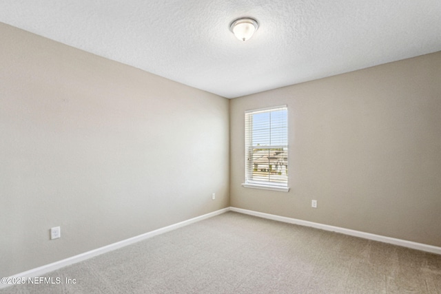 carpeted spare room with baseboards and a textured ceiling