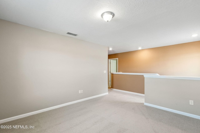 unfurnished room with baseboards, visible vents, light colored carpet, a textured ceiling, and recessed lighting