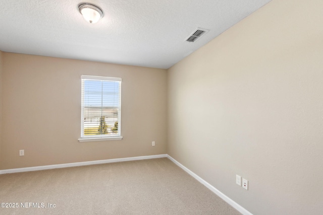 carpeted spare room featuring baseboards, visible vents, and a textured ceiling